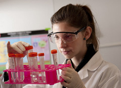 Woman researcher wearing eye and glove protection holding vials